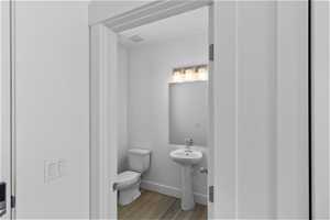 Half bathroom featuring toilet and hardwood / wood-style floors