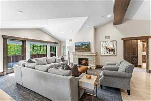 Living room with light hardwood / wood-style floors, a fireplace, and high vaulted ceiling