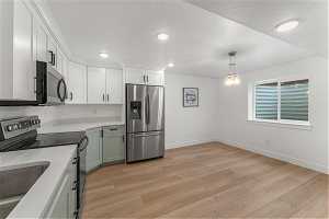 Second Kitchen with light hardwood / wood-style floors, a notable chandelier, decorative light fixtures, white cabinets, and stainless steel appliances