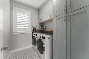 Laundry room featuring separate washer and dryer, cabinets, and light tile floors, built in cabinetry