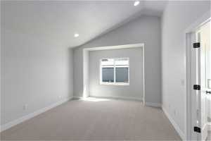 Carpeted spare room with lofted ceiling