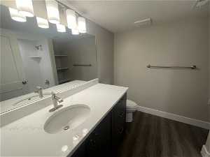 Bathroom with toilet, a textured ceiling, hardwood / wood-style flooring, and oversized vanity