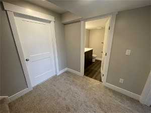 Interior space featuring dark colored carpet, connected bathroom, and a closet