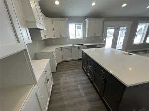 Kitchen featuring a center island, dark wood-type flooring, light stone countertops, white cabinetry, and premium range hood