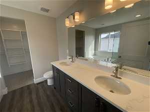 Bathroom featuring toilet, hardwood / wood-style floors, and double vanity