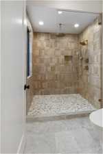 Bathroom with a tile shower, toilet, and tile flooring