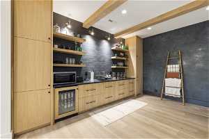 Interior space featuring beverage cooler, light hardwood / wood-style floors, beamed ceiling, light brown cabinetry, and sink