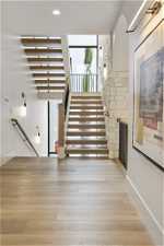 Stairs featuring a stone fireplace and light hardwood / wood-style floors