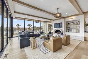 Living room featuring beam ceiling, built in features, an inviting chandelier, and light hardwood / wood-style flooring