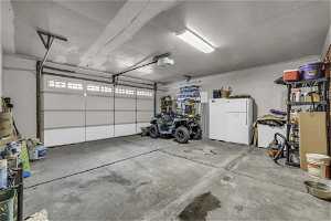 Garage featuring white refrigerator and a garage door opener