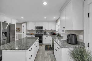 Kitchen featuring white cabinets, a center island, light hardwood / wood-style flooring, stainless steel appliances, and sink