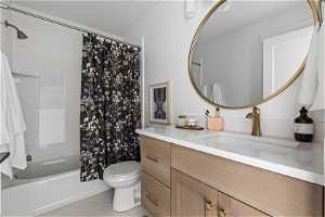 Full bathroom featuring vanity, toilet, tile flooring, and shower / bathtub combination with curtain