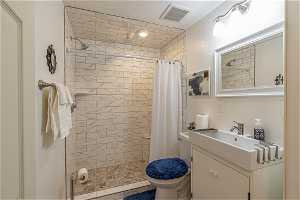 Bathroom featuring a shower with curtain, large vanity, and toilet