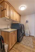 Clothes washing area featuring cabinets, hardwood / wood-style flooring, separate washer and dryer, and a textured ceiling
