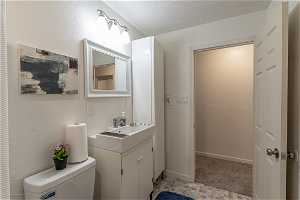 Bathroom with vanity, toilet, a textured ceiling, and tile floors