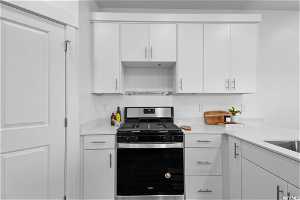 Kitchen featuring white cabinets and stainless steel gas range oven