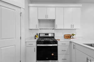 Kitchen featuring white cabinets and stainless steel gas range oven