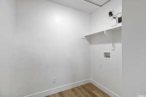 Clothes washing area with light wood-type flooring and washer hookup