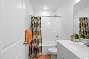 Full bathroom with toilet, large vanity, shower / bathtub combination with curtain, and tile flooring