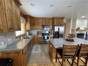 Kitchen with a kitchen bar, a textured ceiling, stainless steel appliances, sink, and tasteful backsplash