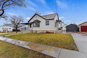 View of front of property featuring a front lawn, a garage, and a porch