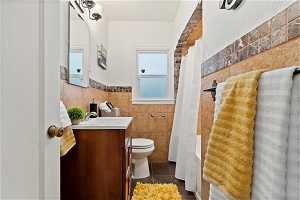 Full bathroom featuring shower / tub combo with curtain, vanity, toilet, tile floors, and tile walls