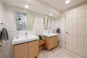 Downstairs  bathroom with double vanity, tile flooring, and backsplash