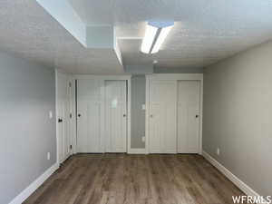 Unfurnished bedroom featuring dark wood-type flooring, multiple closets, and a textured ceiling