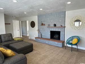 Carpeted living room featuring a textured ceiling and a fireplace