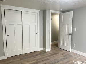 Unfurnished bedroom with a closet, a textured ceiling, and dark hardwood / wood-style floors