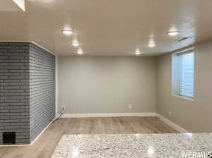 Spare room with light hardwood / wood-style flooring, a fireplace, and a textured ceiling