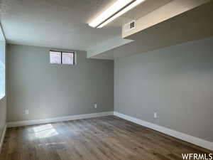 Basement with a textured ceiling and dark hardwood / wood-style floors