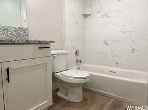 Full bathroom featuring vanity, tiled shower / bath combo, toilet, and hardwood / wood-style floors