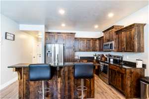 Kitchen with a kitchen island, appliances with stainless steel finishes, dark stone counters, and light hardwood / wood-style flooring