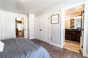 Carpeted bedroom featuring a closet, a textured ceiling, and ensuite bath