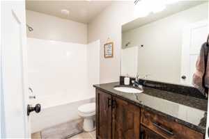 Full bathroom with wood-type flooring, large vanity, shower / bathing tub combination, and toilet