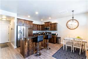Kitchen featuring dark brown cabinets, light hardwood / wood-style flooring, a kitchen island, and stainless steel appliances
