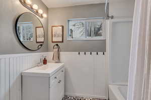 Bathroom with shower / tub combo with curtain, a healthy amount of sunlight, and vanity