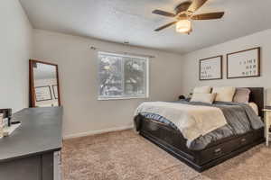 Bedroom featuring a textured ceiling, light carpet, and ceiling fan