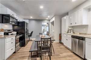 Kitchen featuring white cabinets, a textured ceiling, light hardwood / wood-style floors, and stainless steel appliances