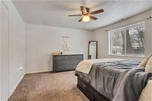 Carpeted bedroom with a textured ceiling and ceiling fan