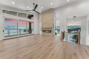 Unfurnished living room with light hardwood / wood-style flooring, a mountain view, a fireplace, and ceiling fan