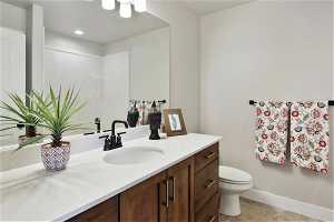 Bathroom featuring tile floors, large vanity, and toilet