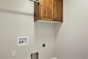 Washroom with cabinets, washer hookup, and hookup for an electric dryer