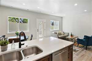 Kitchen with sink, plenty of natural light, light hardwood / wood-style floors, and stainless steel dishwasher