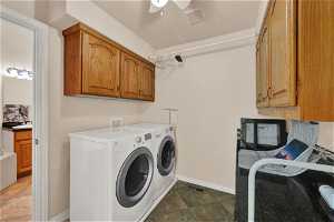 Laundry room with hookup for a washing machine, separate washer and dryer, ceiling fan, dark tile flooring, and cabinets
