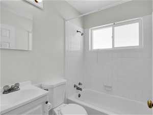 Full bathroom featuring vanity with extensive cabinet space, tiled shower / bath combo, and toilet