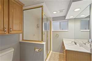 Bathroom with vanity, a textured ceiling, tile floors, toilet, and a shower with shower door