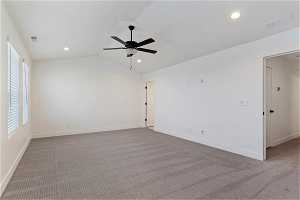 Empty room featuring plenty of natural light, light colored carpet, lofted ceiling, and ceiling fan