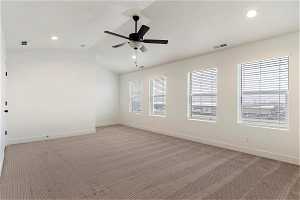 Unfurnished room featuring vaulted ceiling, light colored carpet, and ceiling fan